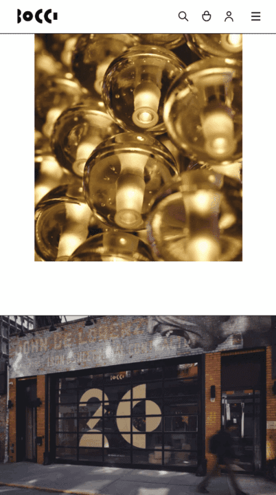Close-up of illuminated Bocci glass light fixtures above a building entrance with large...